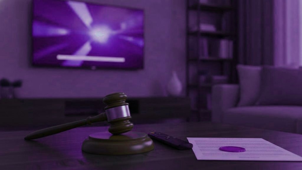 A judge gavel, a streaming remote and a sealed document on a coffee table in front of a TV